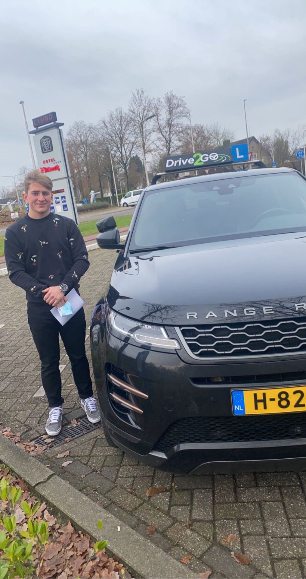 Geslaagde leerling met rijbewijs bij de lesauto