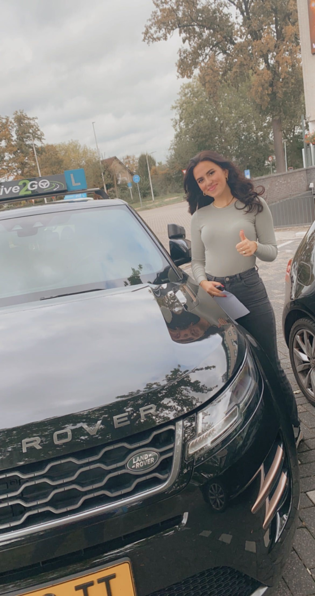 Geslaagde leerling naast de lesauto van Drive2Go